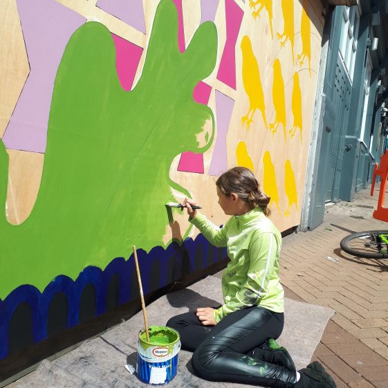 A young artist from Brunts Academy finishing painting in a large green oak leaf on the mural | Mansfield Townscape Heritage Project